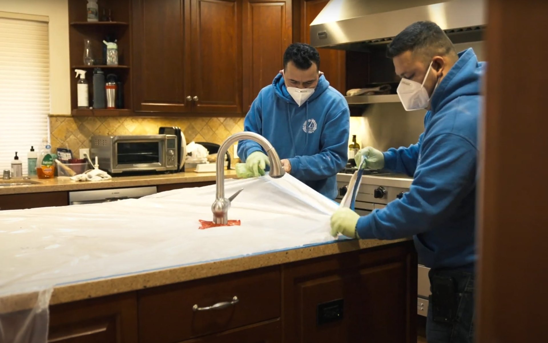 Expert water damage cleanup and restoration services in Friendswood Professional water damage restoration technicians cleaning kitchen countertops and sink area with protective equipment