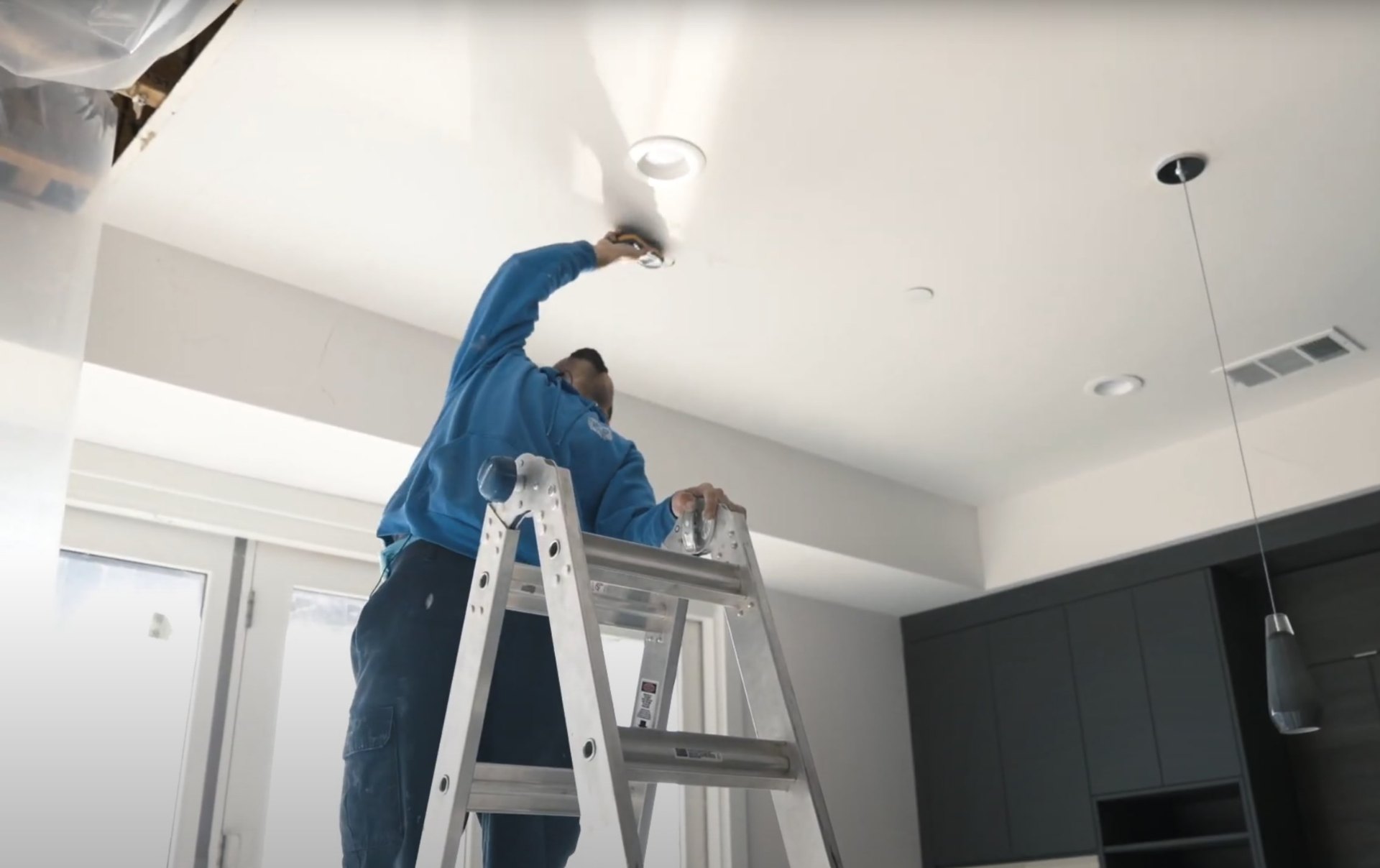 Professional ceiling water damage restoration and repair services Water damage restoration specialist working on ceiling repair with professional ladder and equipment